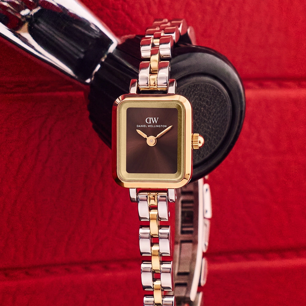 Close crop of a wrist wearing a gold watch from the new season